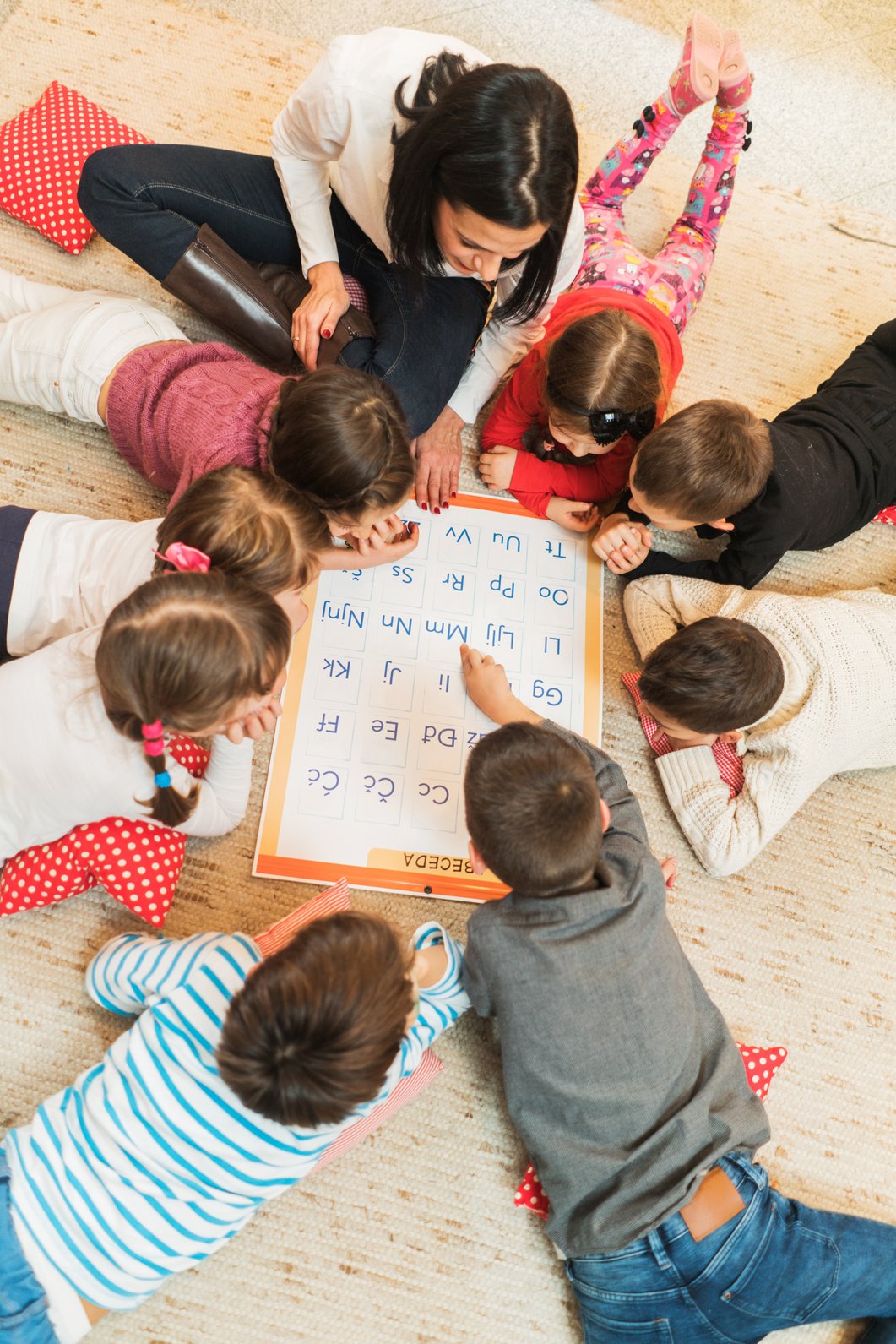 Above view of teacher and kids learning in preschool.